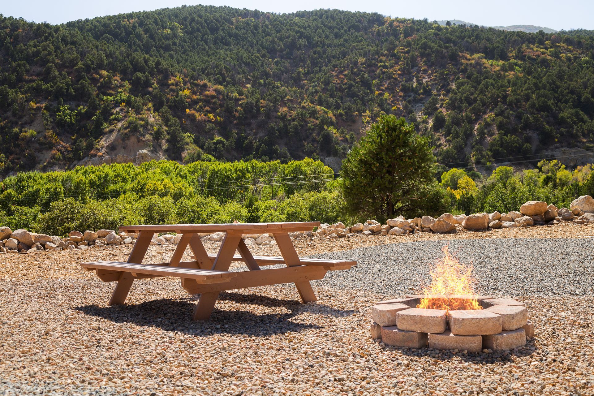 A picnic table and a fire pit with mountains in the background