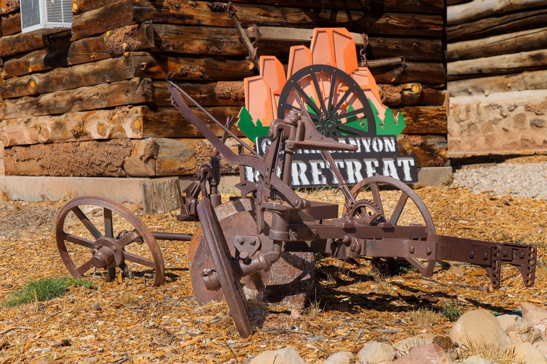 An old plow sits in front of a canyon retreat sign