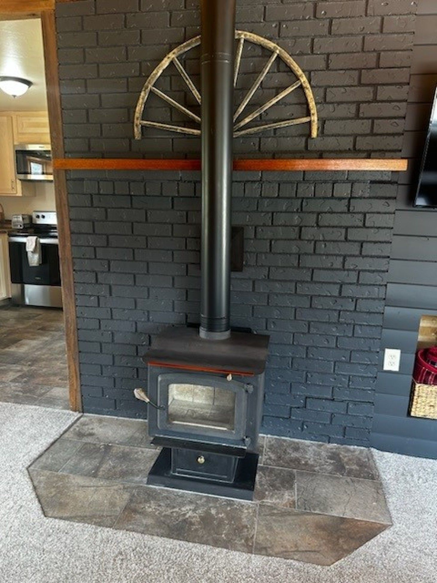 A wood stove is sitting in front of a black brick wall.