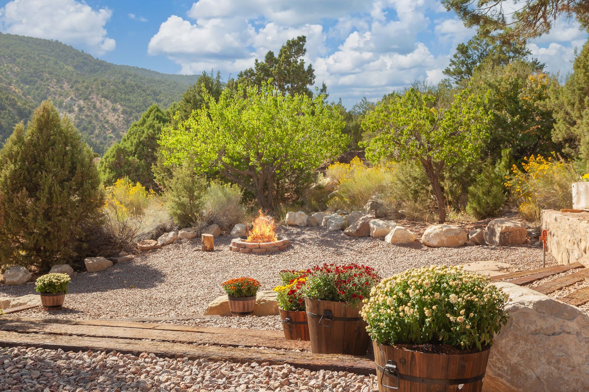 A fire pit is in the middle of a rocky area surrounded by trees.
