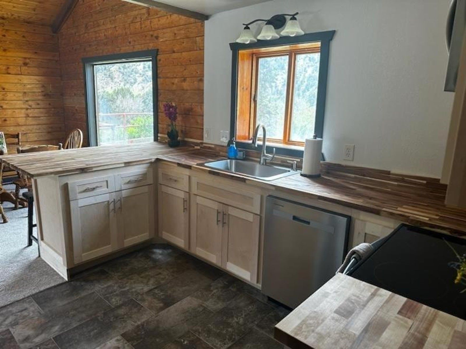A kitchen with a sink , dishwasher , and wooden counter tops.