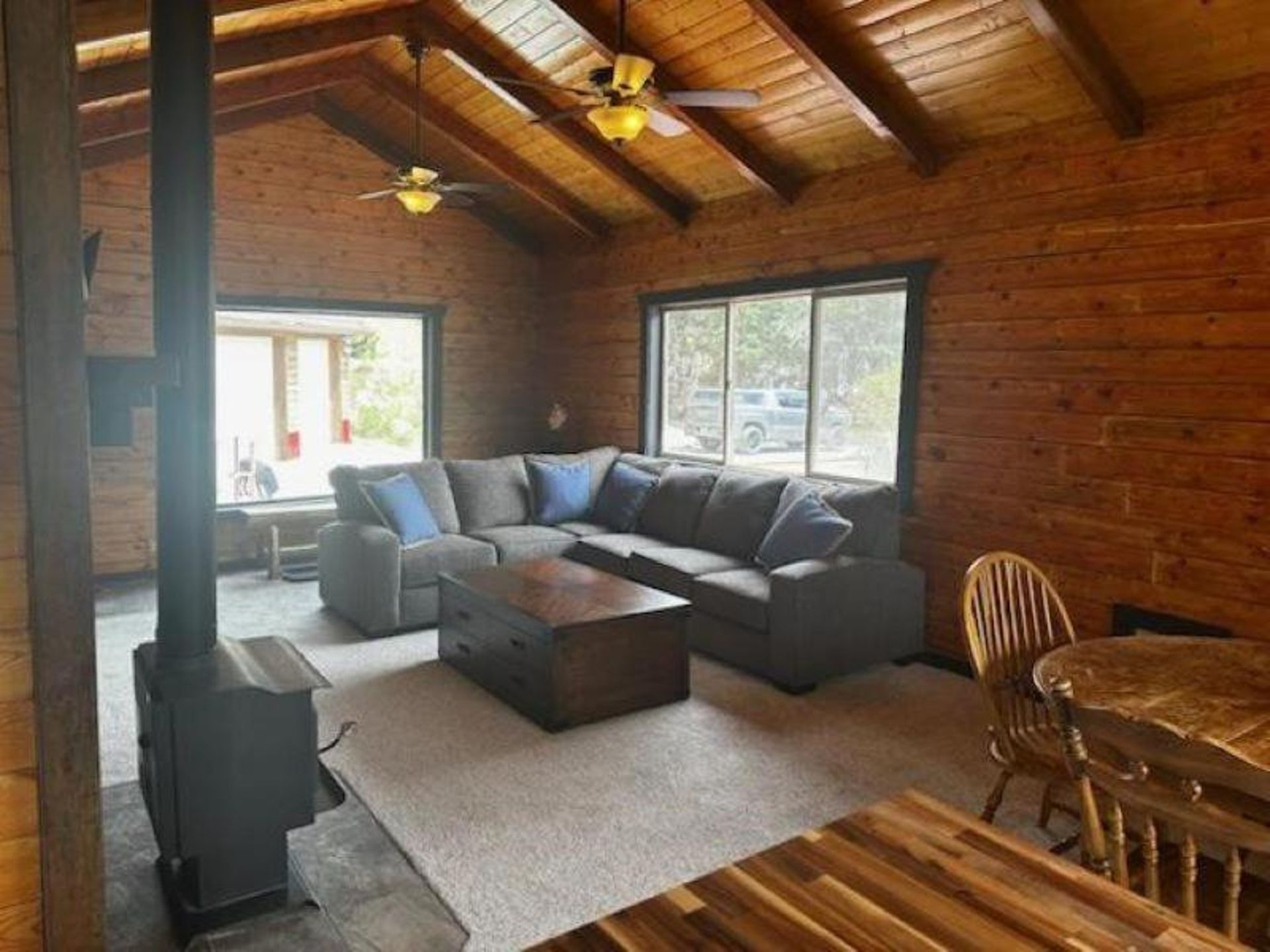 A living room in a log cabin with a couch , table and chairs.