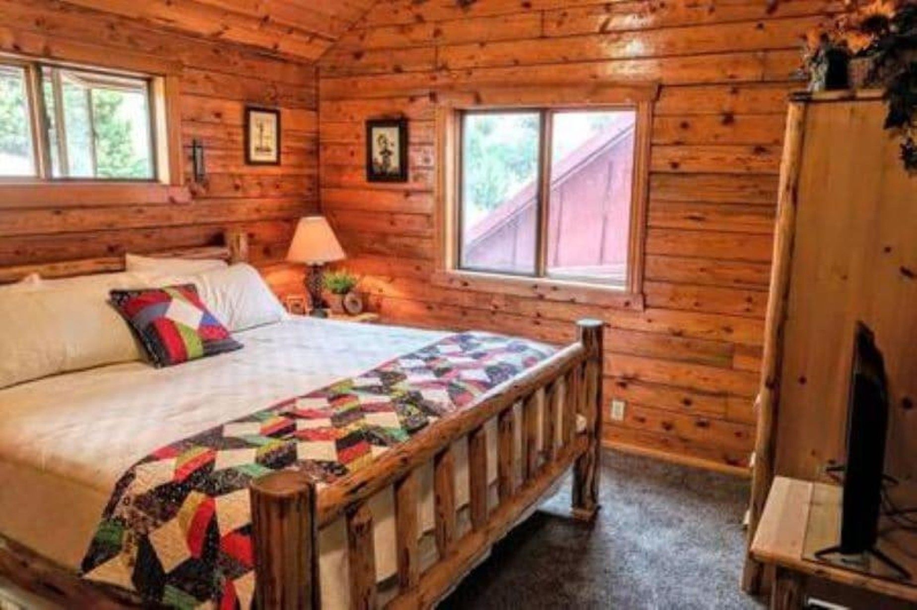 A bedroom in a log cabin with a bed and a window.