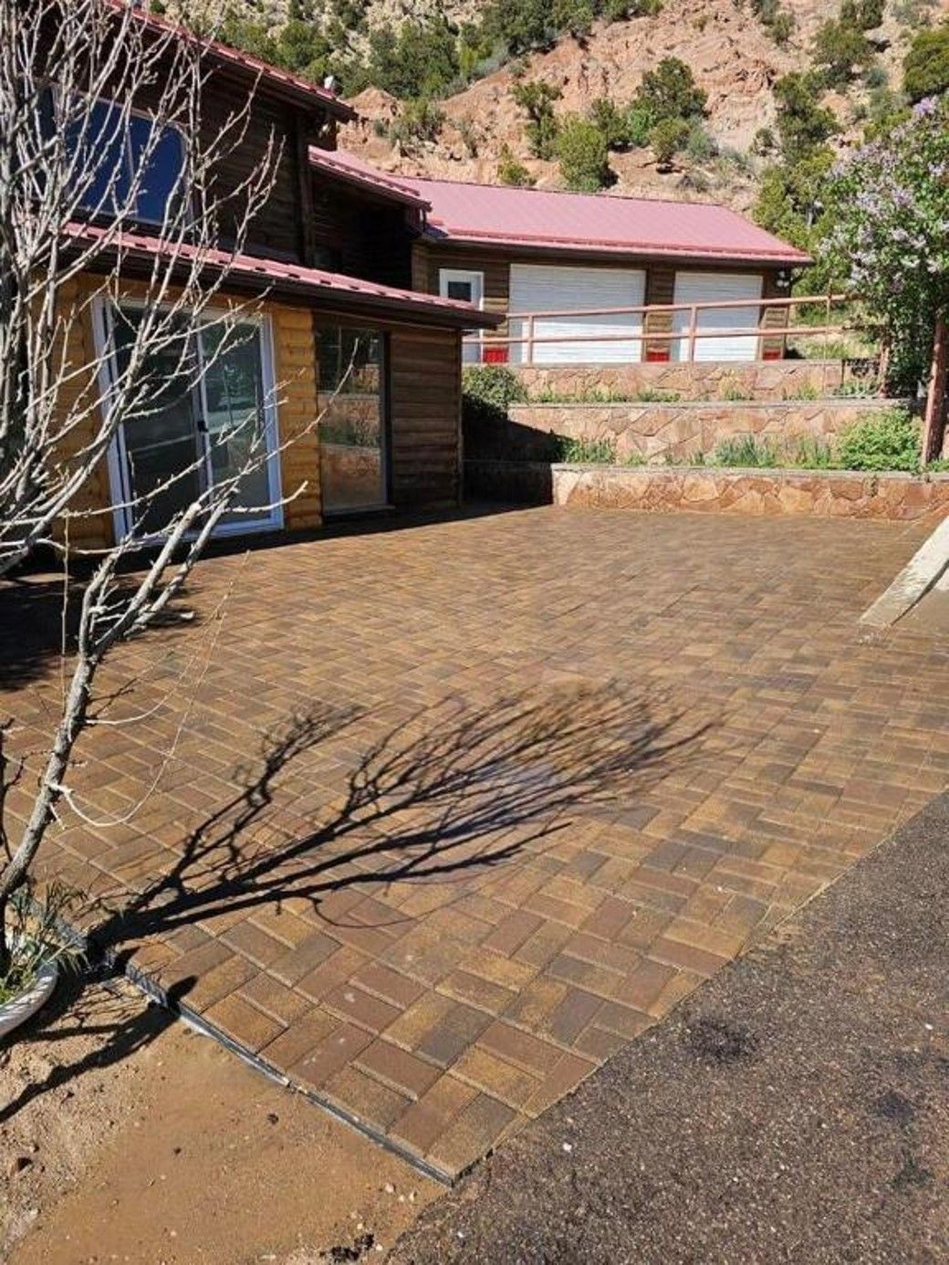 A house with a red roof and a brick driveway in front of it