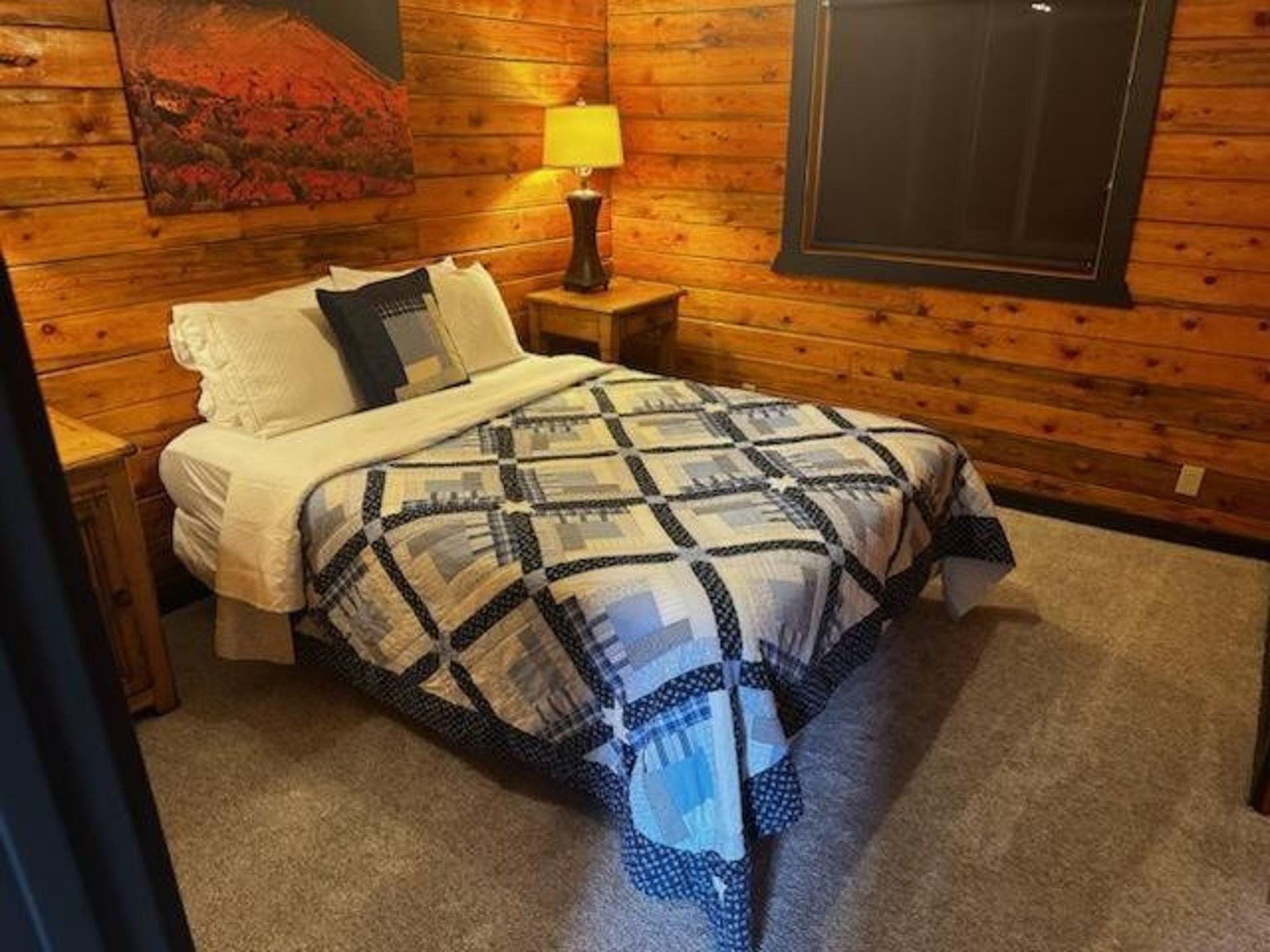 A bedroom in a log cabin with a bed and a window.