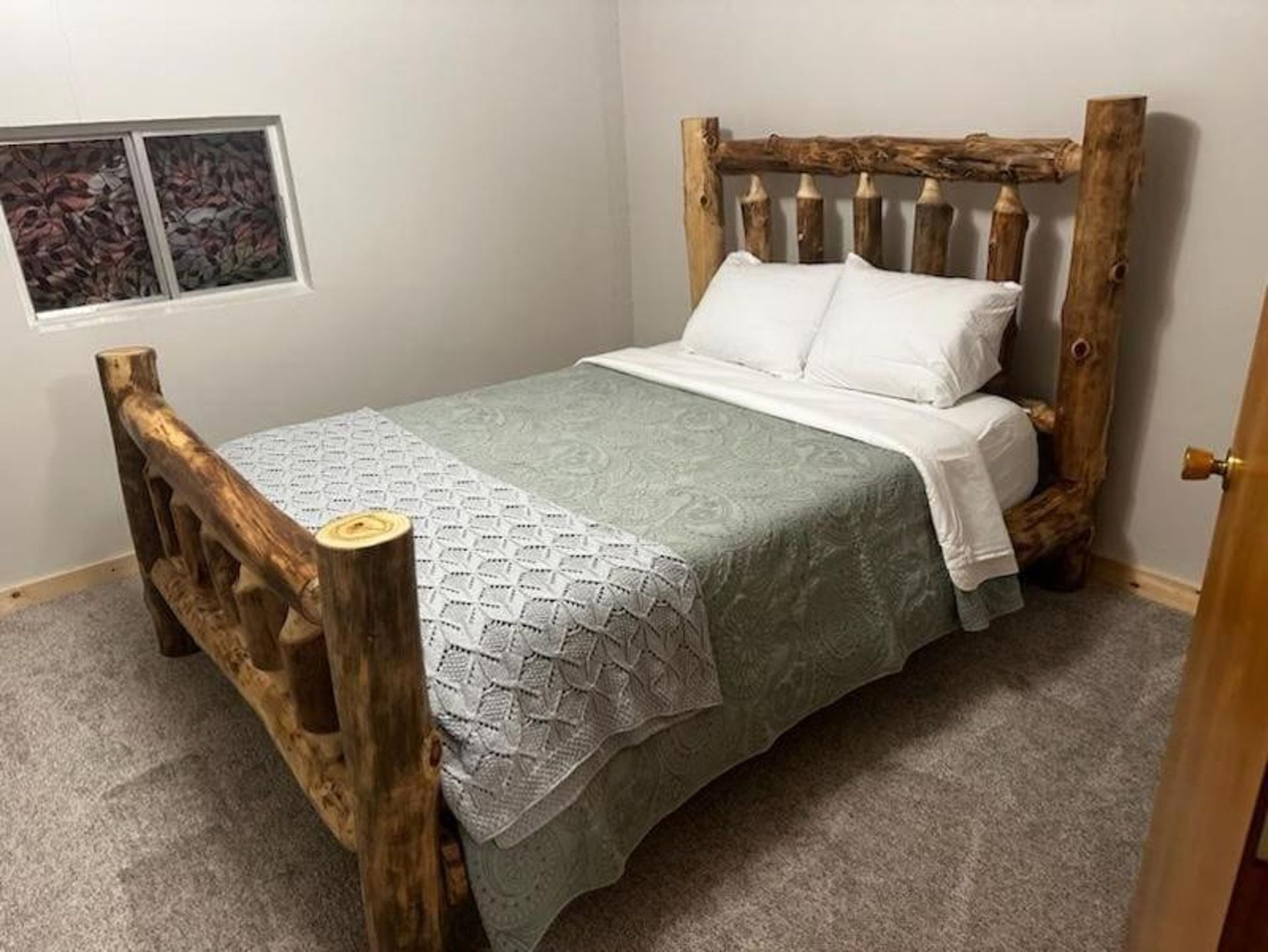 A bedroom with a log bed and a window.