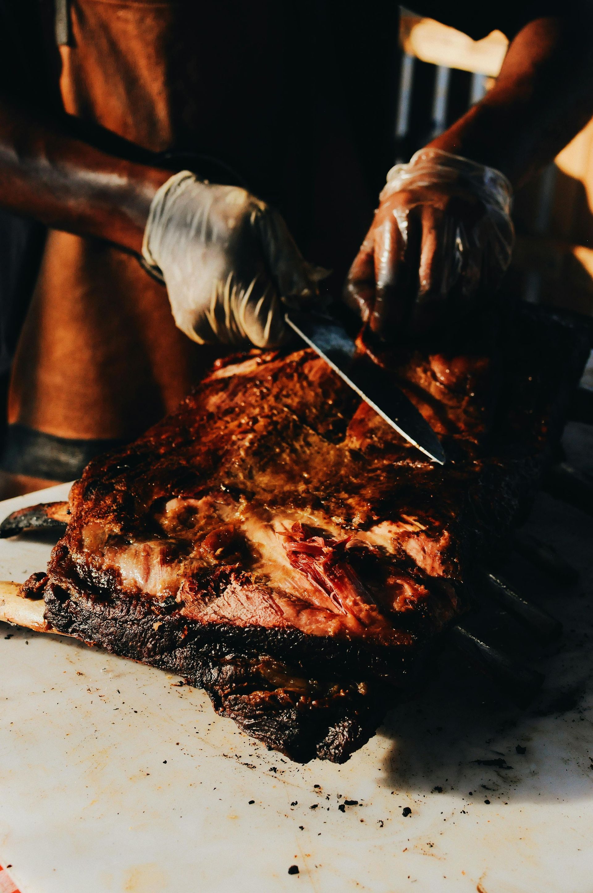 A person is cutting a large piece of meat on a cutting board.
