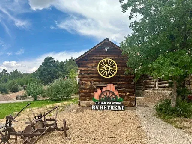 A log cabin with a wagon wheel on the side of it.
