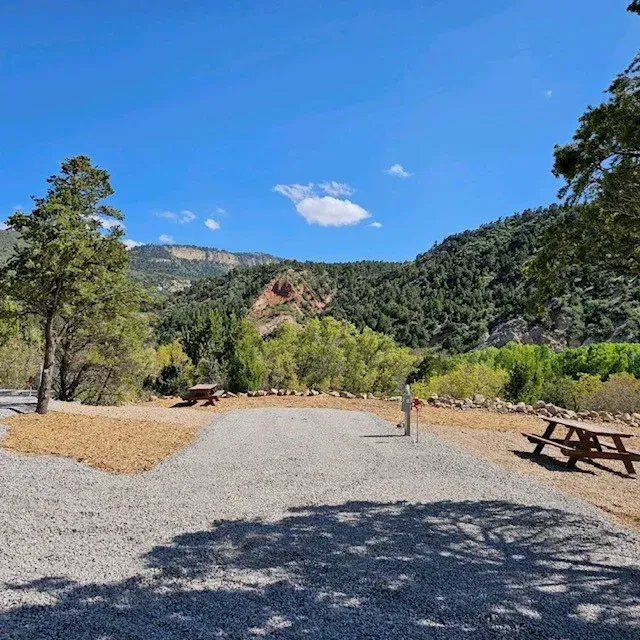 A gravel road with a picnic table in the foreground and mountains in the background