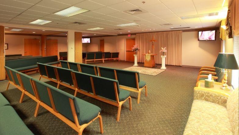 A large room with rows of green chairs and a podium