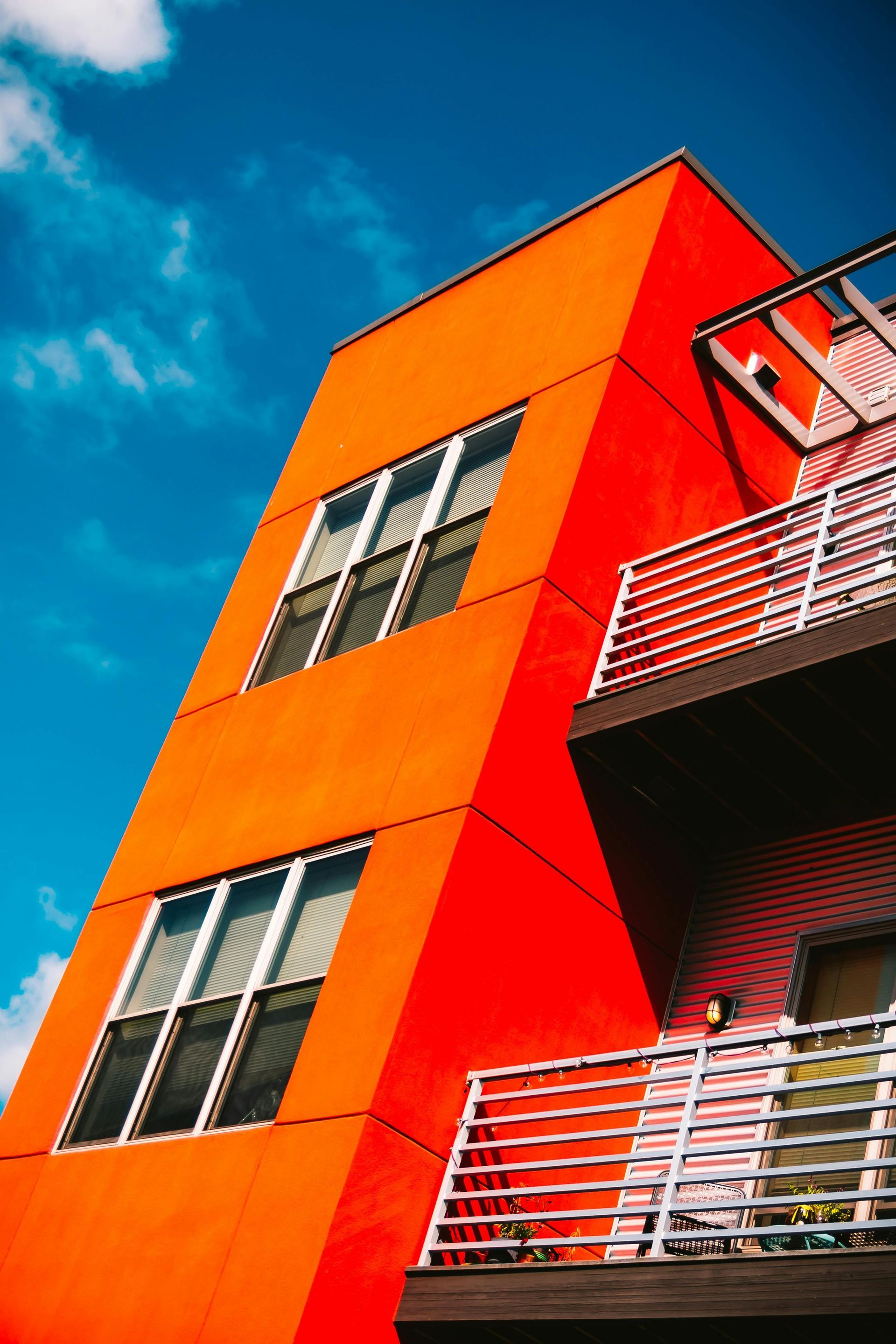 A red building with a balcony and a blue sky in the background.