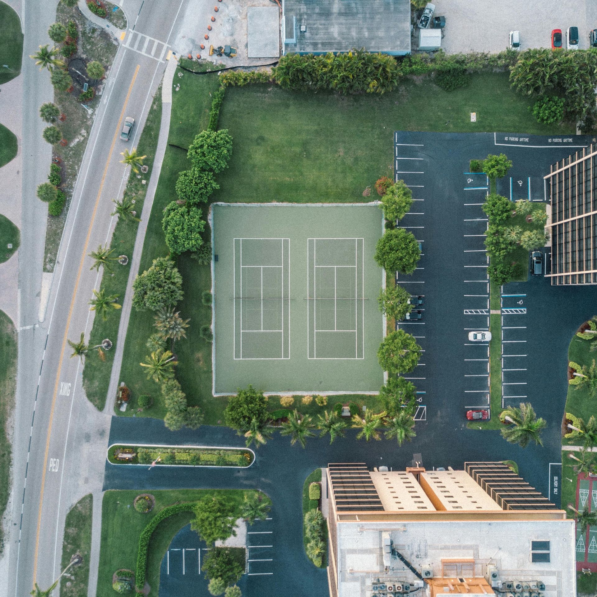 An aerial view of a tennis court and parking lot