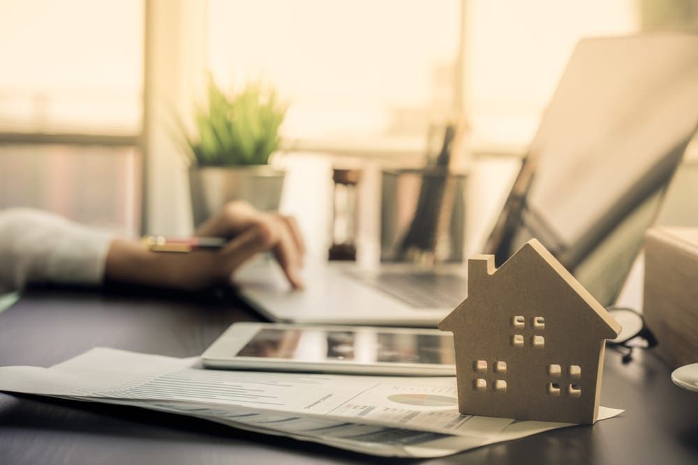 A Model House Is Next To A Person Using A Laptop — GMS Legal & Conveyancing In 38 Canton Beach Rd Toukley, NSW