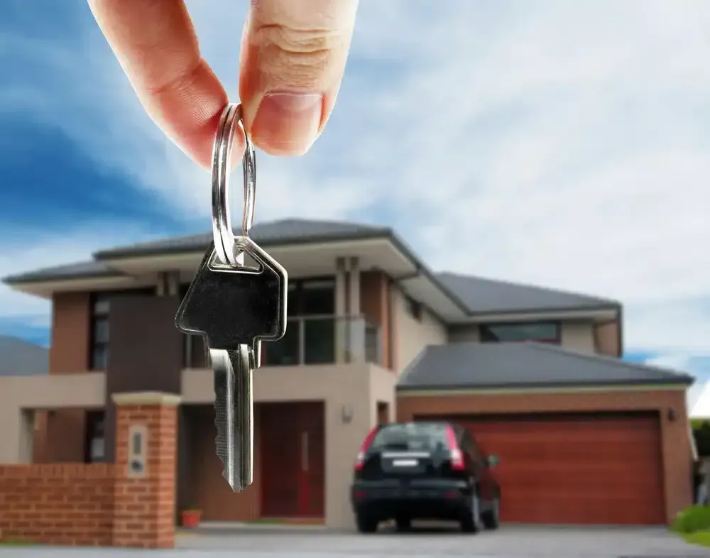 Hand holding keys in front of a modern house and car, likely symbolizing homeownership.  GMS Legal & Conveyancing In 38 Canton Beach Rd, Toukley