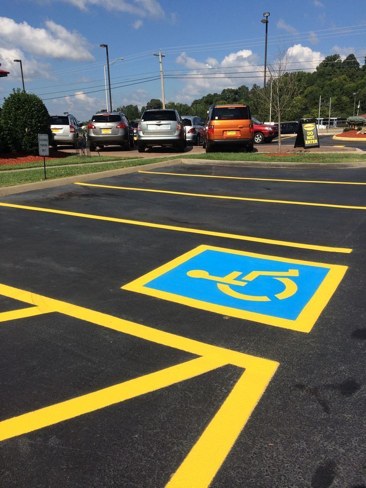 Accessible parking space marked in blue and yellow lines in a parking lot.