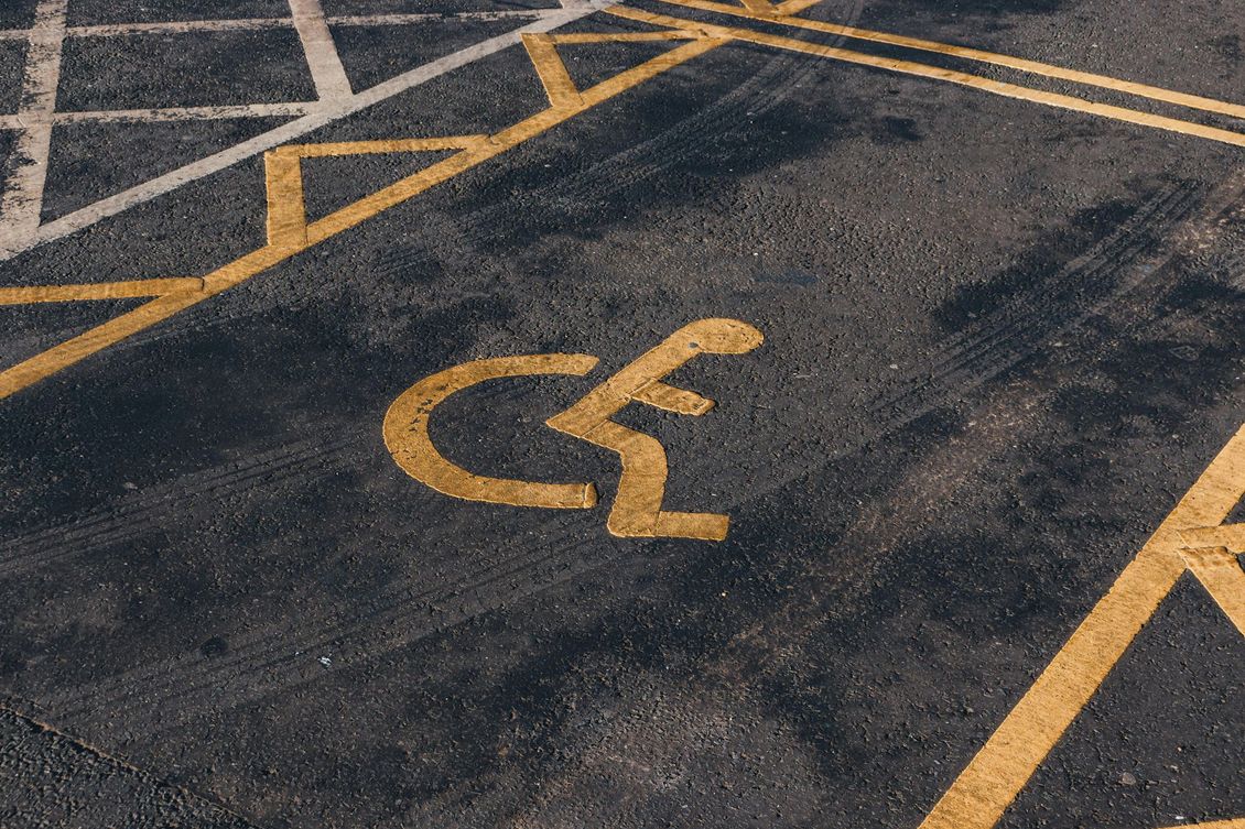 Yellow handicap parking symbol painted on dark asphalt in a marked parking space