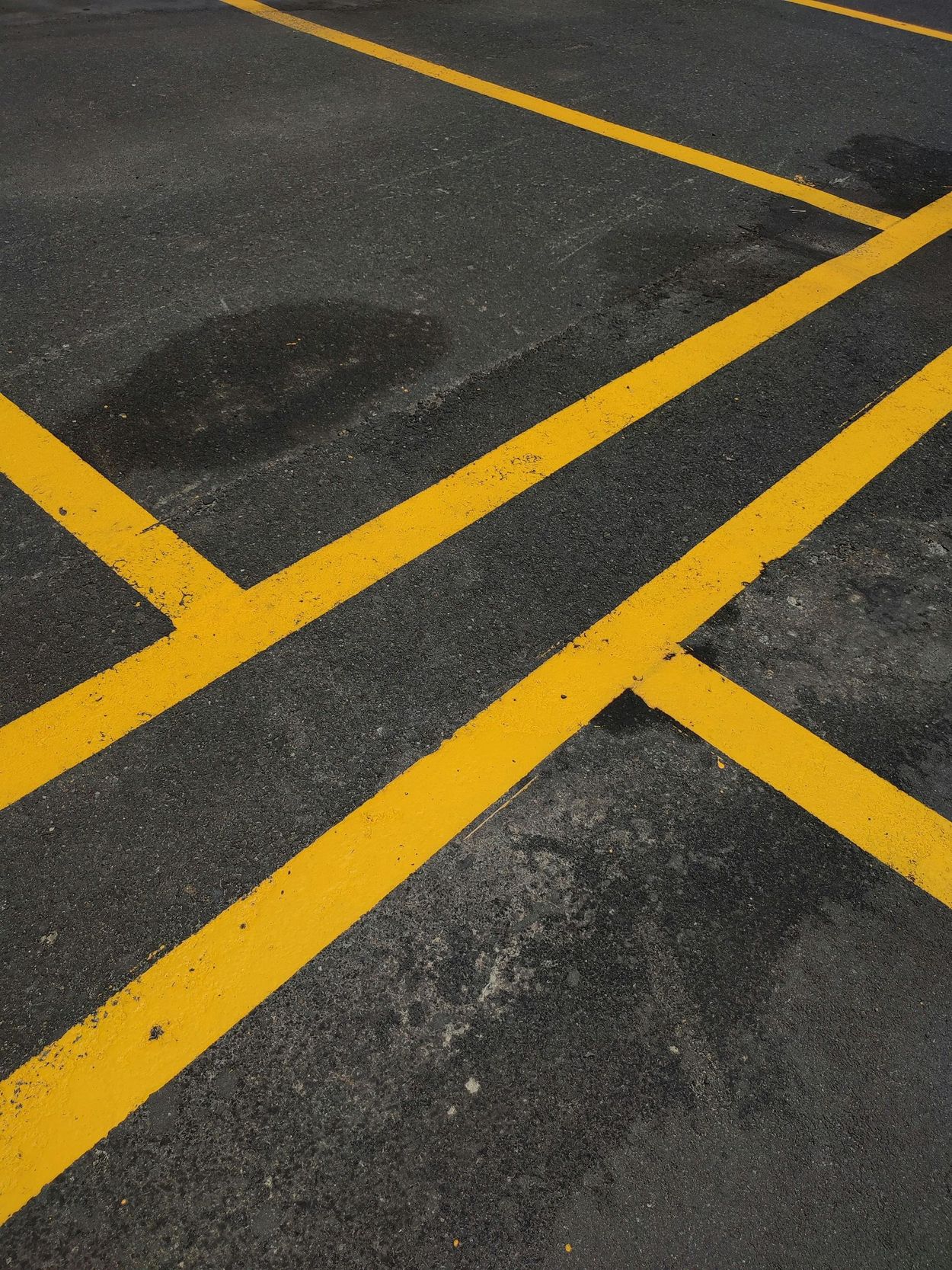 Yellow crosshatched road markings on dark asphalt pavement with a few wet patches