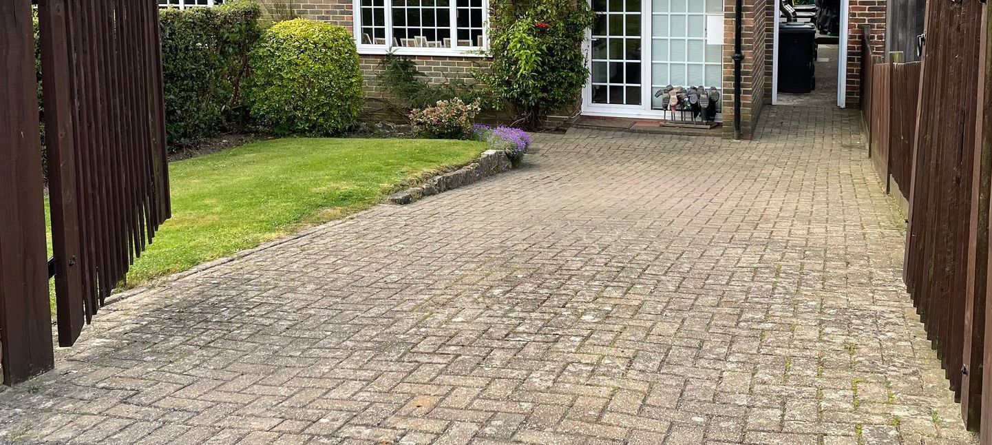 A gravel driveway leading to a house with a wooden fence.
