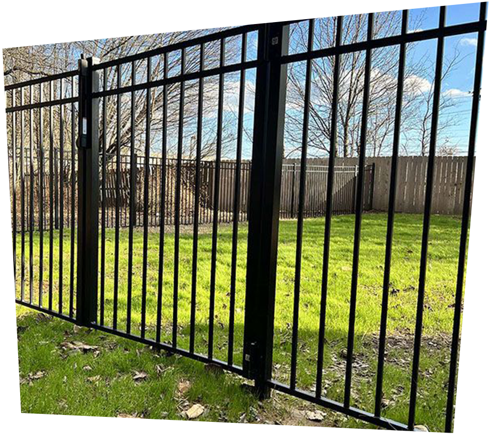 A black wrought iron fence surrounds a lush green field.