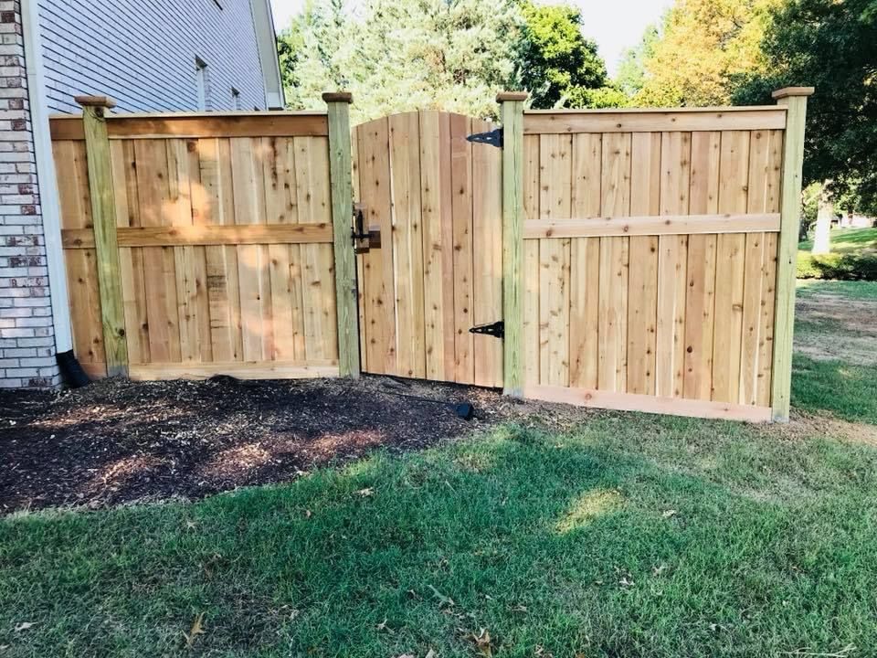 Wooden fence with gate, set against a brick wall and green lawn.