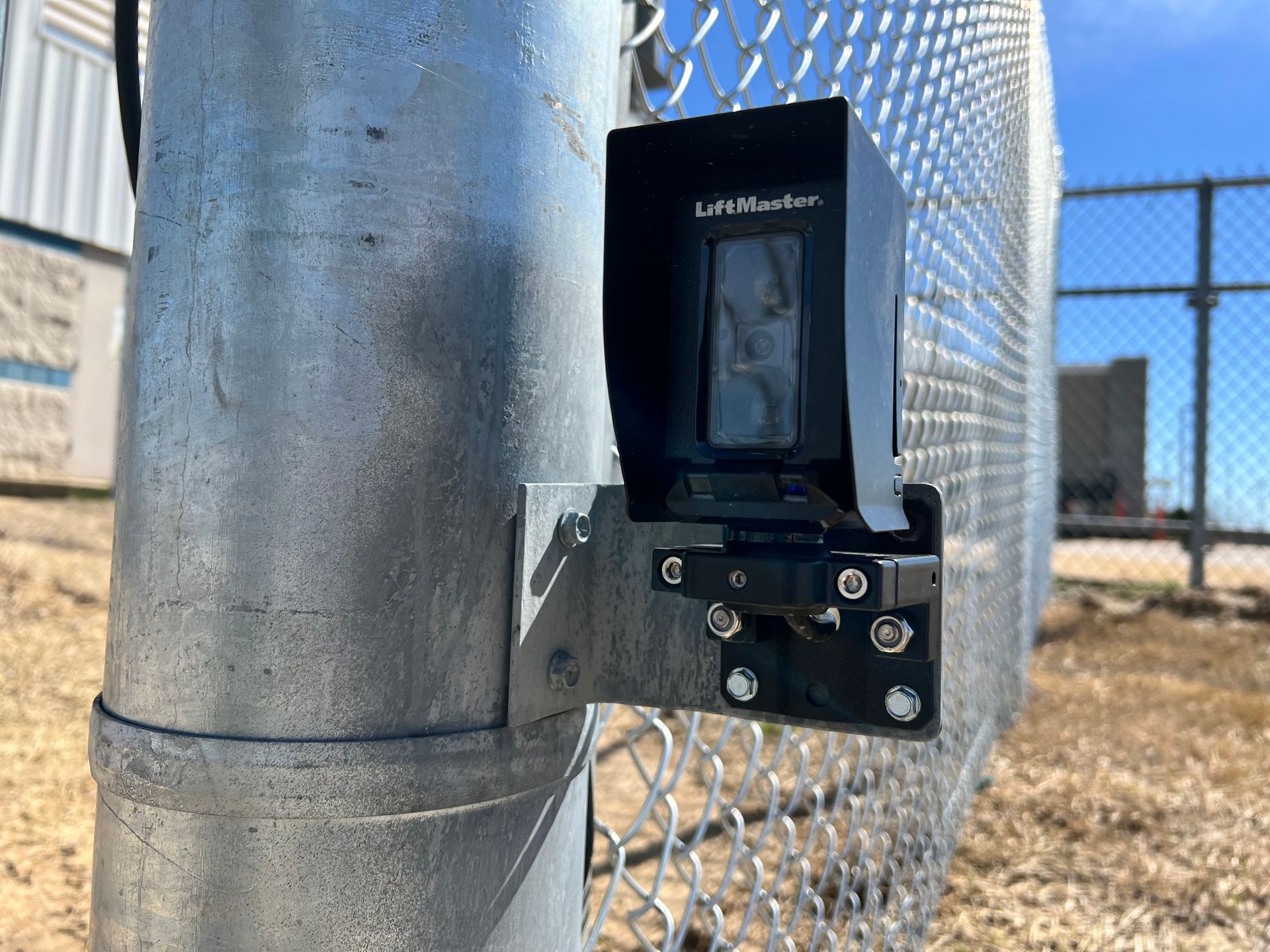 Black LiftMaster sensor mounted on a metal fence post.