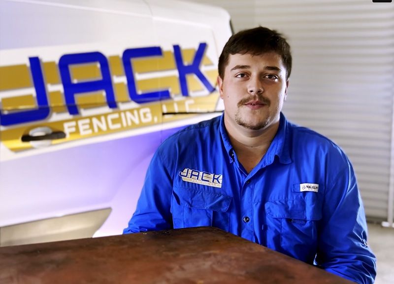 A man in a blue shirt is standing in front of a jack fencing van