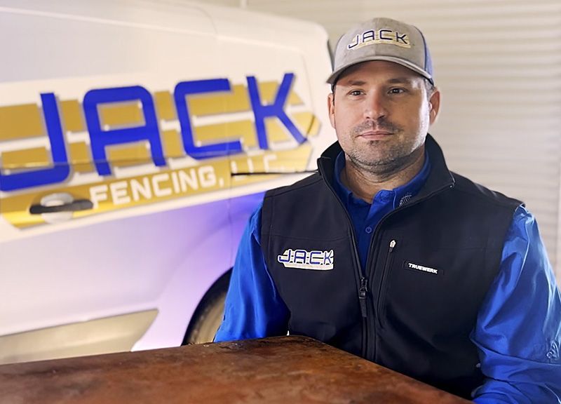 A man is standing in front of a jack fencing truck