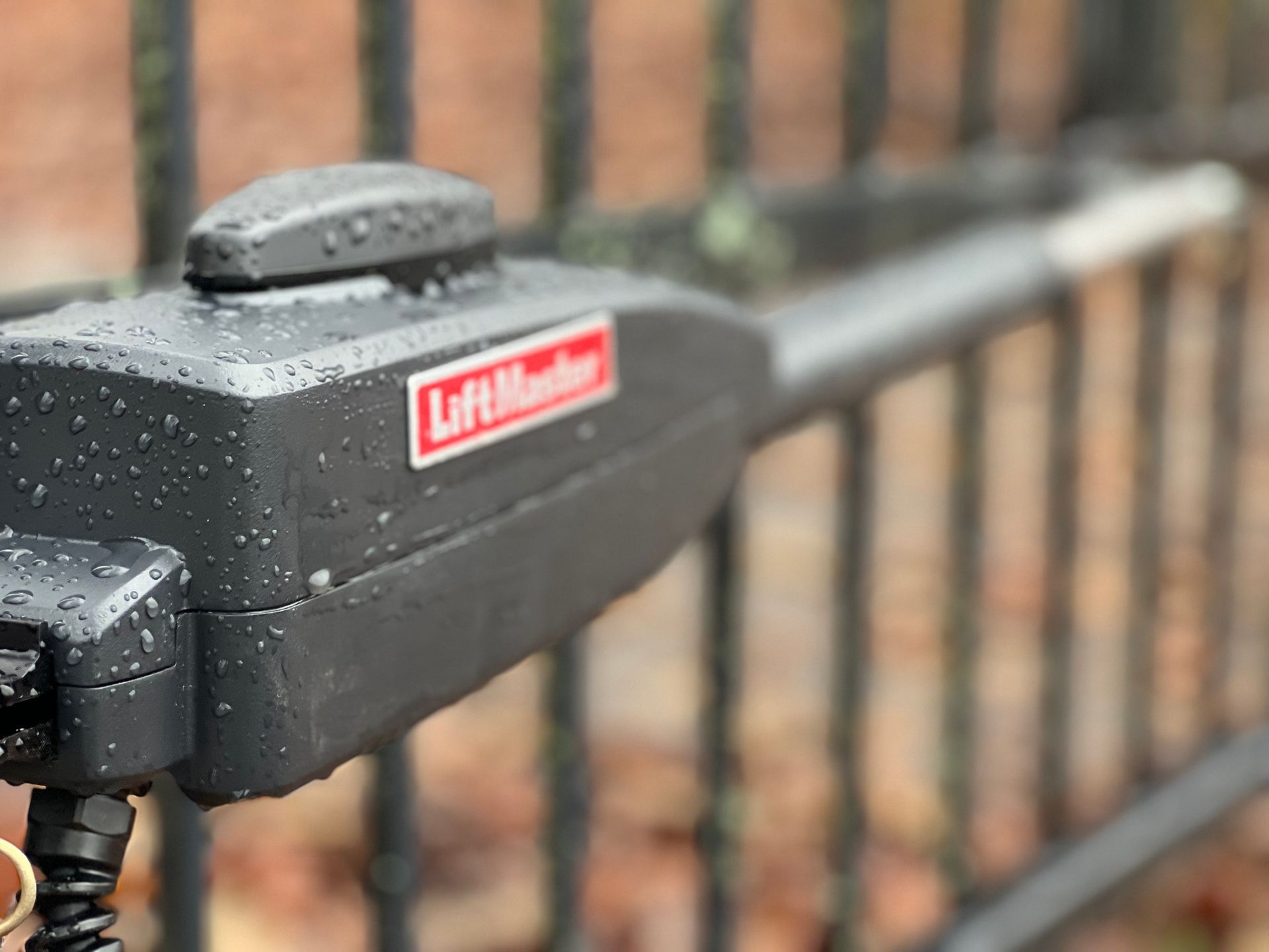 A close up of a liftmaster gate opener on a fence.