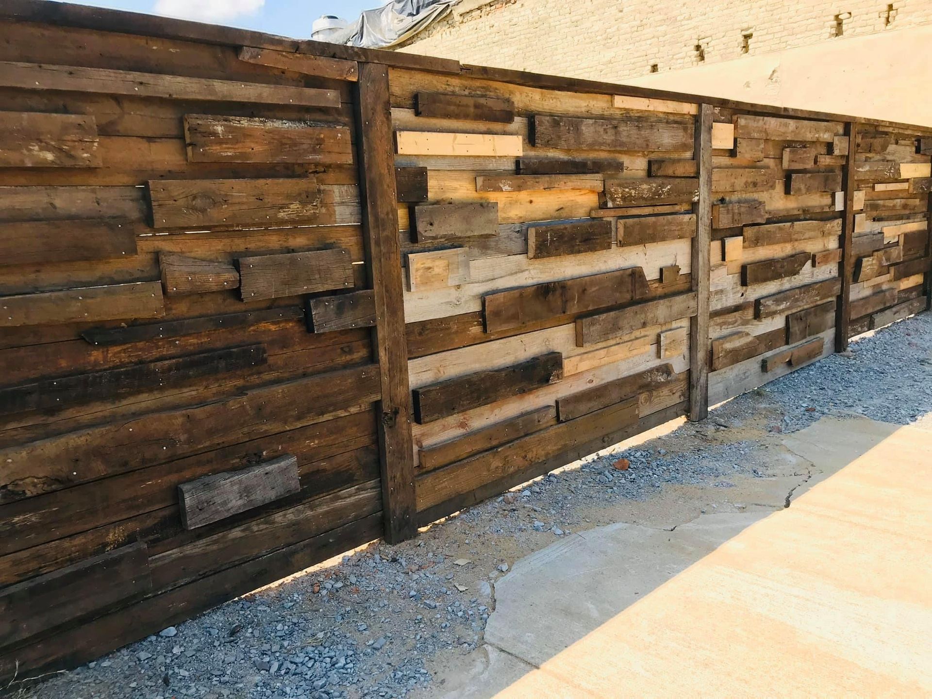 A wooden fence made of wooden boards is sitting on top of gravel.