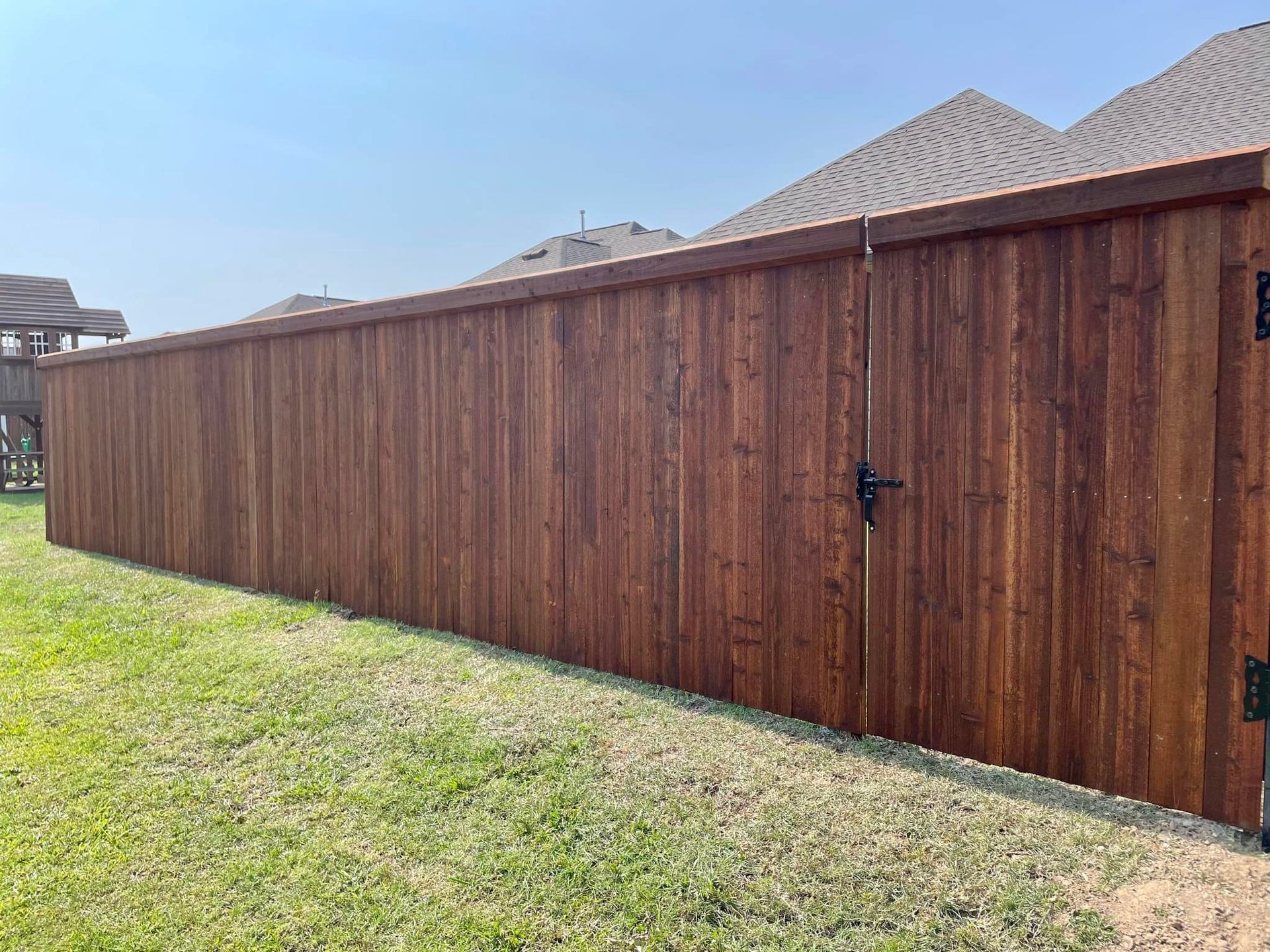 A wooden fence with a gate in the backyard of a house.