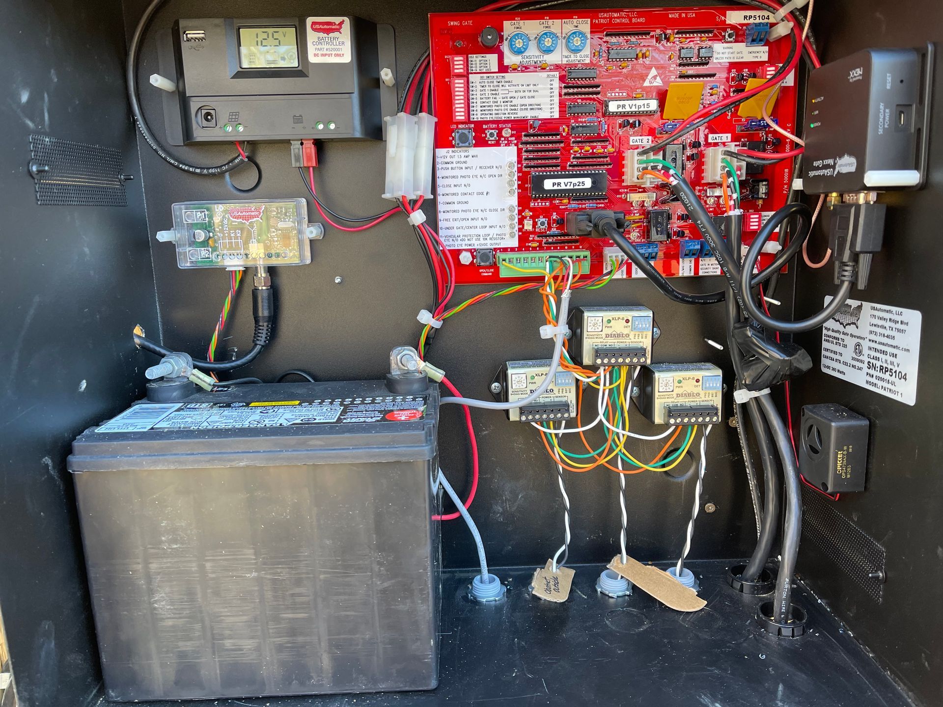 Inside of a black box is a battery, circuit boards, and electrical components. Wires connect the devices.