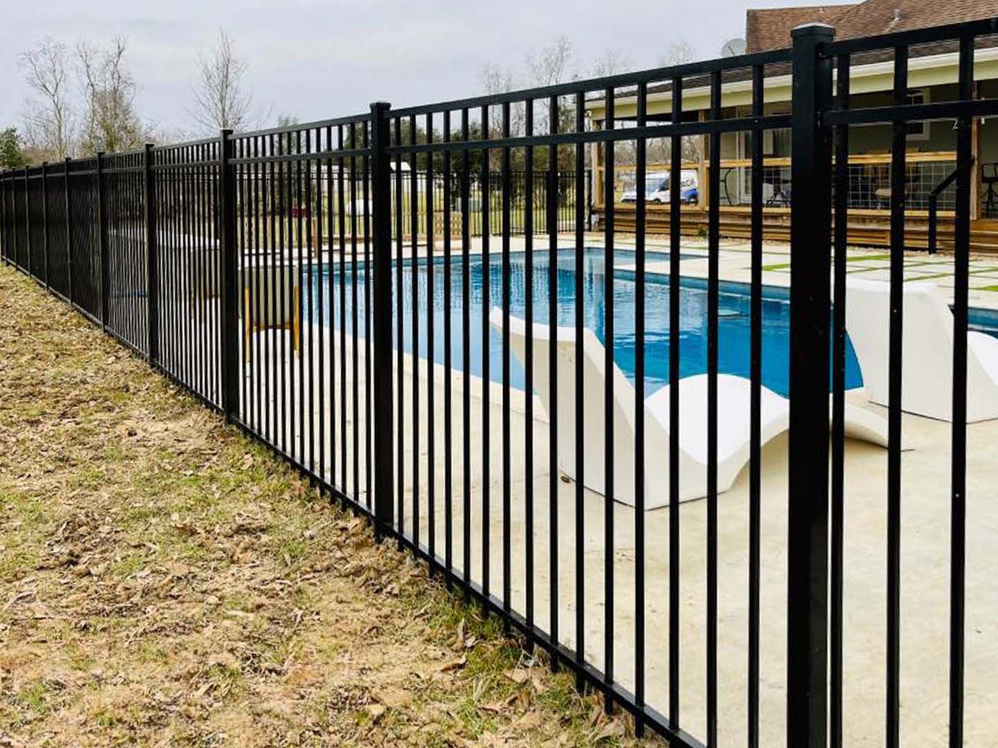 A black metal fence surrounds a swimming pool.