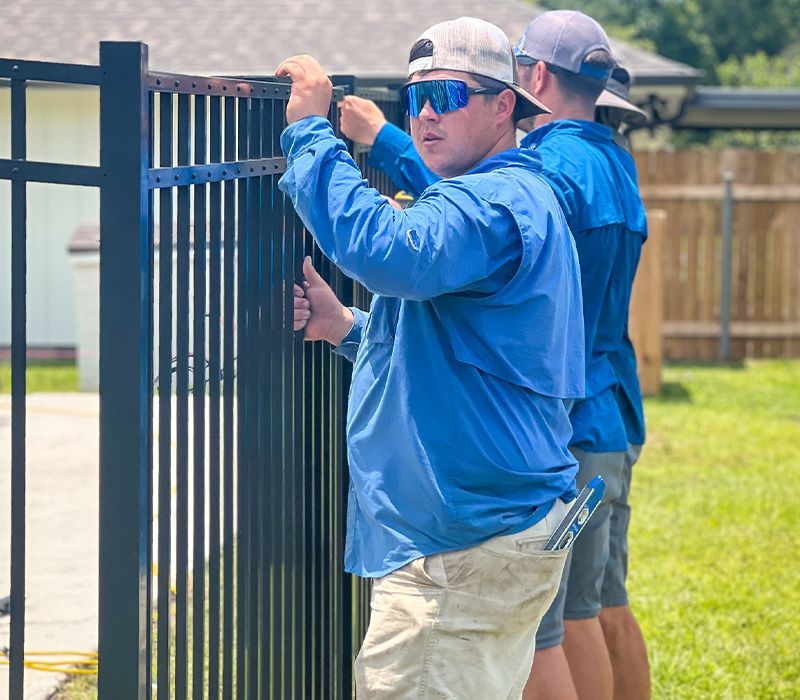 A group of men are working on a metal fence.