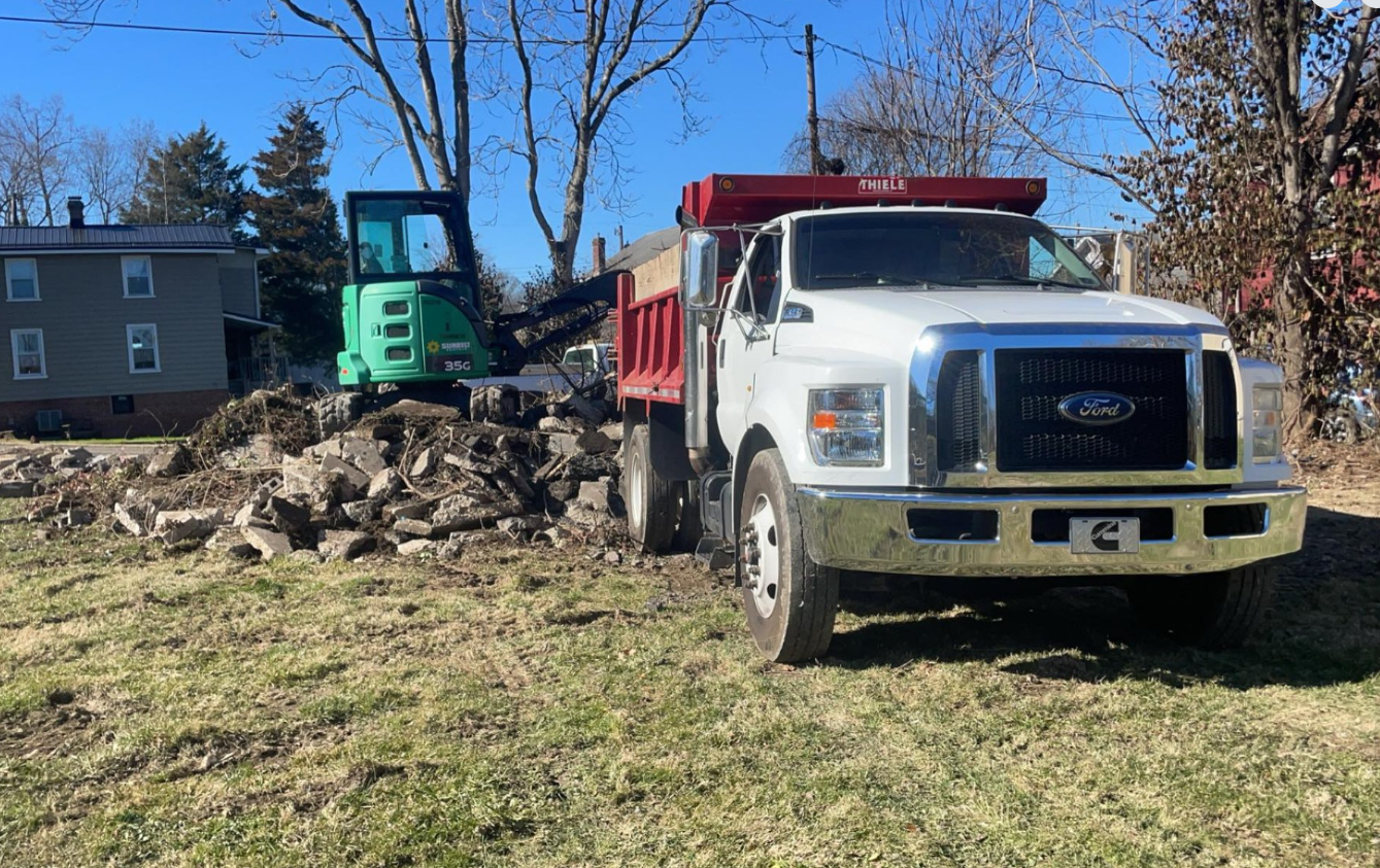 Yellow dump truck carrying gravel at a construction site on a sunny day.