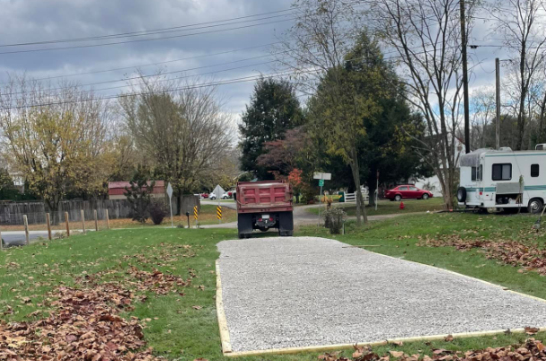 Construction workers installing cables in a trench, excavator and dump truck on a construction site.