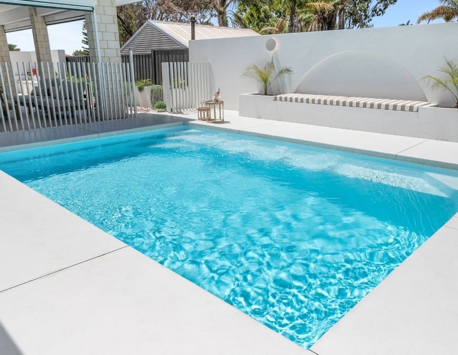 Clean backyard swimming pool with clear blue water, tiled edges and modern outdoor seating area