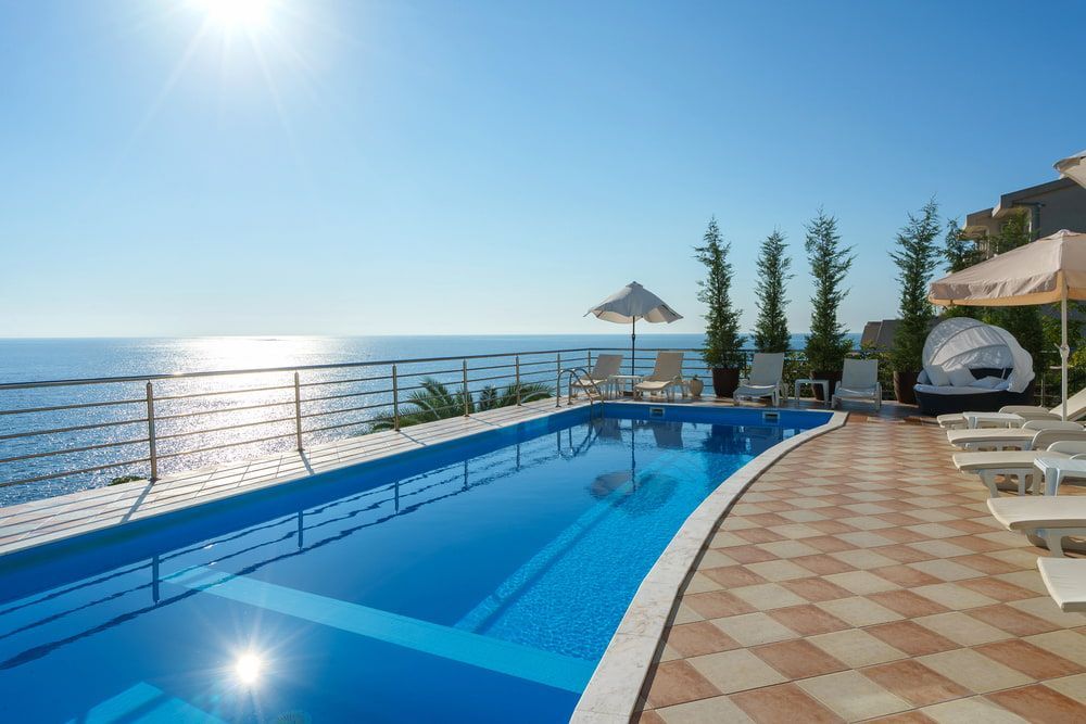 A Large Swimming Pool Surrounded by Chairs and Umbrellas Overlooking the Ocean — Aqualine Pools in Kalkie, QLD