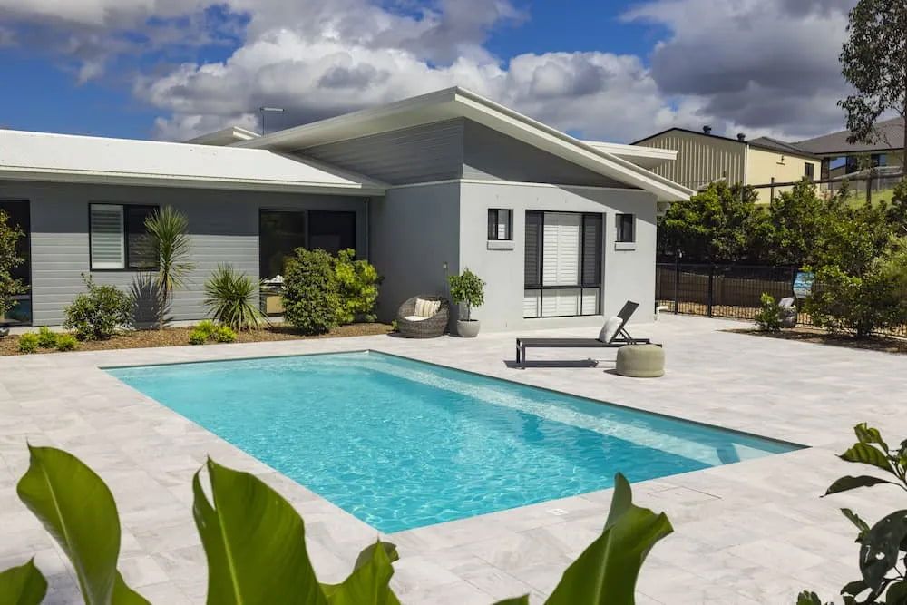 A House With a Large Swimming Pool in Front of It — Aqualine Pools in Childers, QLD