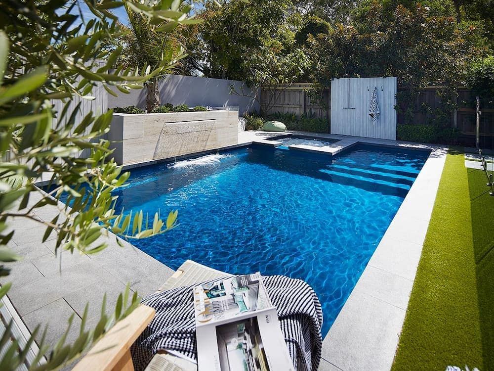 A Large Swimming Pool With a Magazine on a Table in Front of It — Aqualine Pools in Childers, QLD
