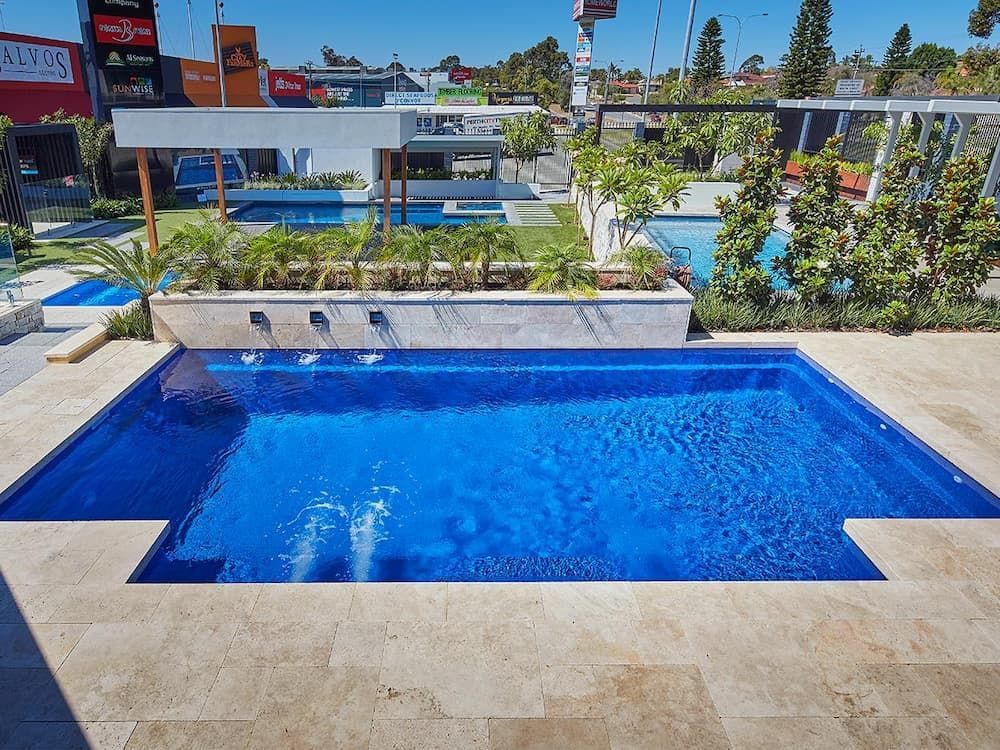 A Large Blue Swimming Pool With a Building in the Background — Aqualine Pools in Childers, QLD