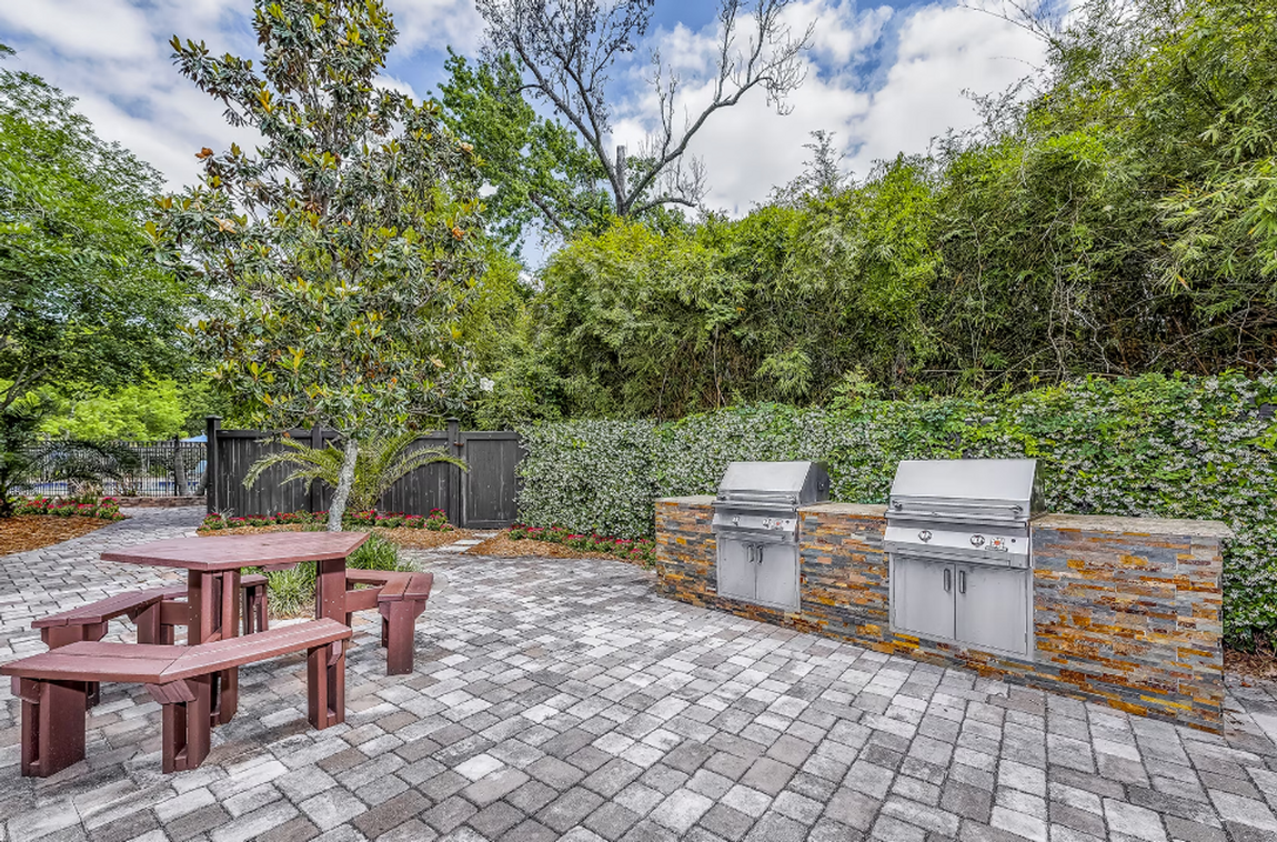 A patio with a picnic table and two grills.