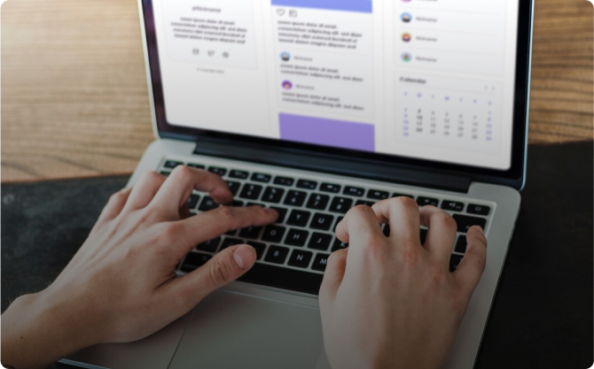 A person is typing on a laptop with a purple screen