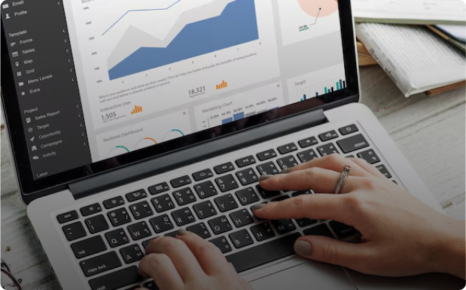 A person is typing on a laptop computer with a graph on the screen.