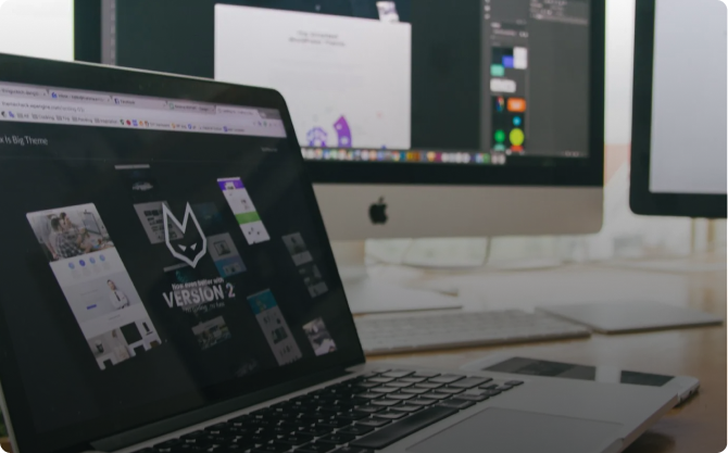 A laptop computer is open on a desk next to a computer monitor.