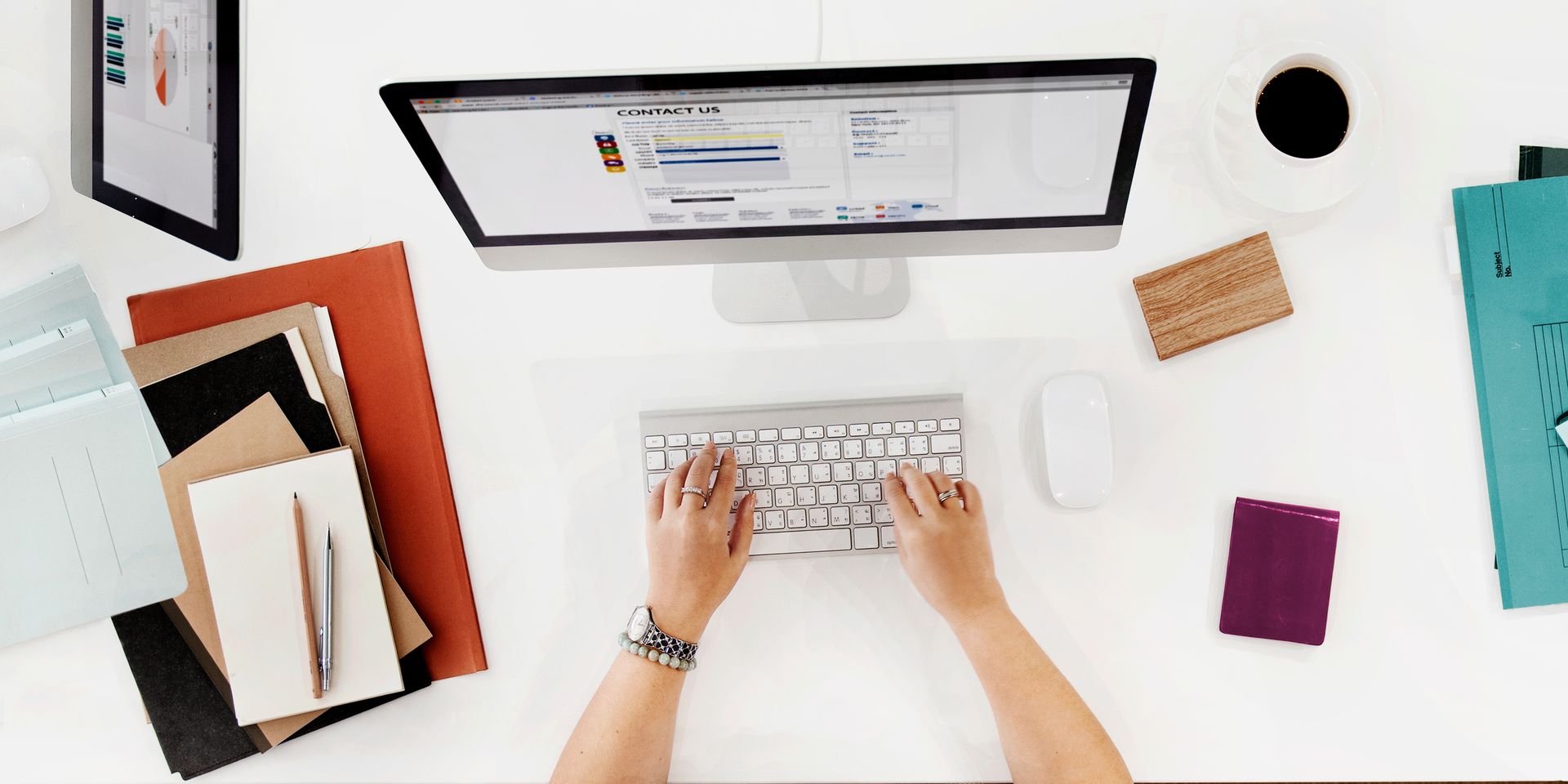 A person is typing on a keyboard in front of a computer.