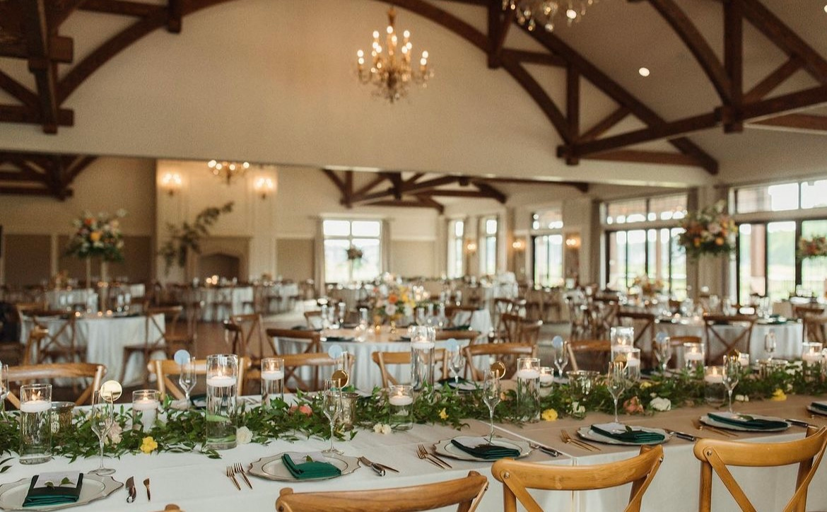 A large room with tables and chairs set up for a wedding reception.
