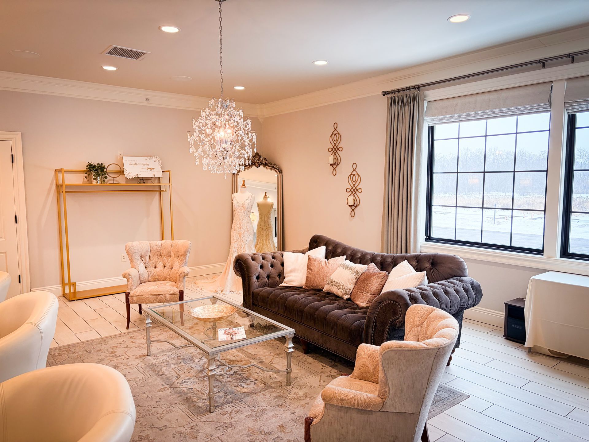 Elegant room with a tufted brown sofa, crystal chandelier, and large window.