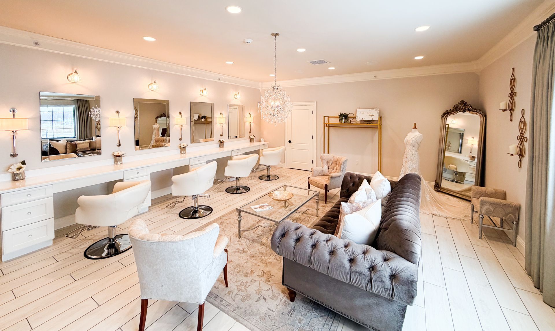 Hair salon with white vanities, chairs, mirrors, and a gray sofa.