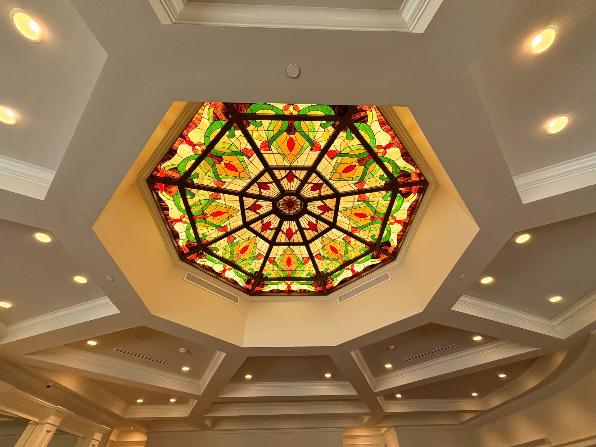Octagonal stained-glass ceiling inset in a white-walled room with recessed lighting.