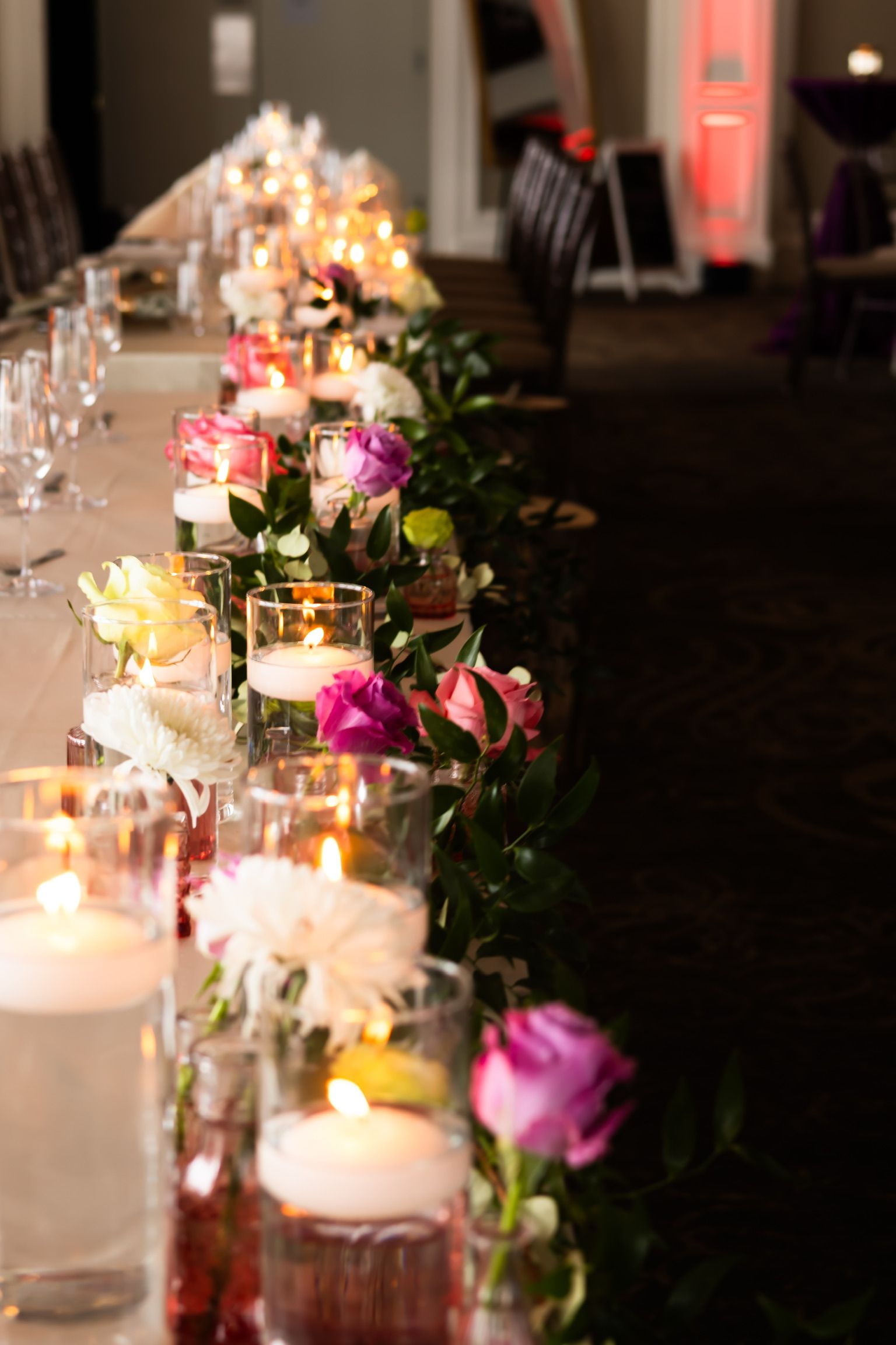 Long table with floating candles and floral garland, likely a wedding reception.